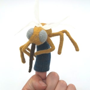 May include: A yellow felt finger puppet of a mosquito with gray eyes, brown proboscis, and white felt wings.