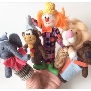 May include: Five finger puppets, including a clown, monkey, elephant, lion, and bear. The puppets are made of felt and have embroidered details.