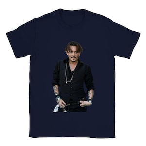 May include: A navy blue t-shirt featuring a photo of Johnny Depp. Depp is wearing a black vest, a black shirt, and a silver necklace. He is looking at the camera.