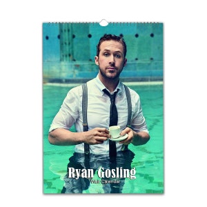 Puede incluir: Un calendario de pared con una foto de Ryan Gosling con una camisa blanca y tirantes, sosteniendo una taza de café. La foto está tomada con un fondo de piscina azul. El texto "Ryan Gosling Wall Calendar" está impreso en la parte inferior de la imagen.