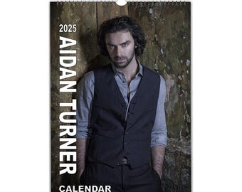 May include: 2025 Aidan Turner Calendar featuring a photo of Aidan Turner in a dark vest and a light blue shirt, standing against a textured wall.