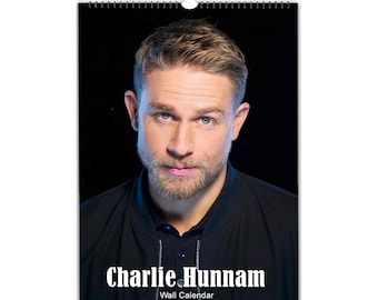 Könnte beinhalten: Ein Wandkalender mit einem Nahaufnahmeporträt von Charlie Hunnam. Das Bild ist in Schwarzweiß gehalten, und Hunnam blickt direkt in die Kamera. Der Text "Charlie Hunnam" ist in Weiß unter dem Bild gedruckt, und der Text "Wandkalender" ist in Weiß darunter gedruckt.