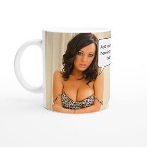 May include: White ceramic mug with a photo of a woman wearing a leopard print bra. The text "Add your own caption here in the bubble" is in a speech bubble.