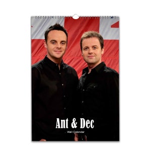 Könnte beinhalten: Ein Wandkalender mit einem Foto von Ant und Dec, zwei britischen Fernsehmoderatoren, vor einem rot-weiß-blauen Hintergrund. Der Text "Ant & Dec" ist in weißen Buchstaben unter dem Foto gedruckt, darunter in kleineren weißen Buchstaben der Text "Wandkalender".