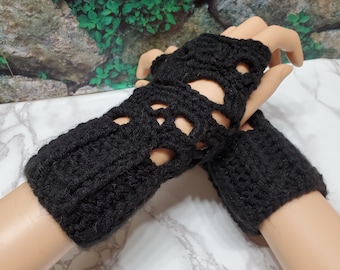 May include: Black crocheted fingerless gloves with a skull design. The gloves are made with a chunky yarn and have a loose fit.
