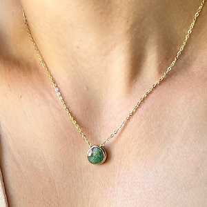 May include: A gold chain necklace with a green gemstone pendant. The pendant is a teardrop shape and has a gold setting.
