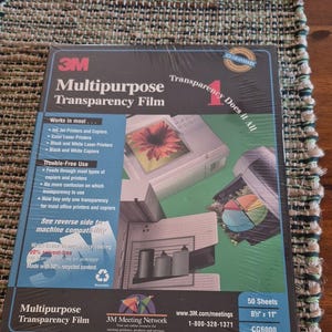May include: A package of 3M Multipurpose Transparency Film containing 50 sheets measuring 8.5 inches by 11 inches. The black box features blue and white text, a graphic of a printer, and a colorful pie chart. It is labeled as solvent-free.