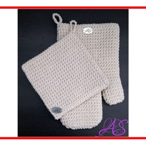May include: A set of two crocheted pot holders in a cream color. The pot holders have a textured design and feature a small silver tag with the initials "AS".
