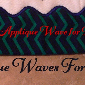 Op de afbeelding: Een witte spuugdoek met een blauw en groen zigzagpatroon en een gegolfde rand. De tekst "Finished Applique Wave for Burp Cloth" is in rood op de doek geborduurd. De tekst "1721 Applique Waves For Burp Cloth" is in zwart onder de doek geschreven.