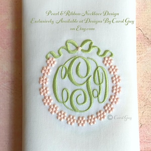 May include: A green embroidered monogram with a pearl and ribbon design. The monogram is surrounded by a circle of pink embroidered flowers. The text "Pearl & Ribbon Necklace Design Exclusively Available at Designs By Carol Guy on Etsy.com" is at the top of the image. The text "Carol Guy" is at the bottom of the image.