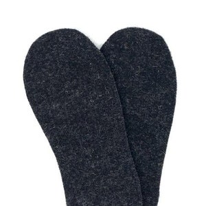 May include: A pair of black felt insoles for shoes or boots. The insoles are made of a soft, fuzzy material and are designed to provide warmth and comfort.
