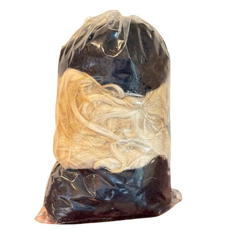 May include: A plastic bag containing two bundles of hair extensions. One bundle is black and the other is blonde.