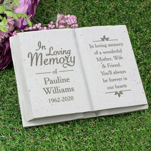 May include: A white, book-shaped memorial stone with the words "In Loving Memory of Pauline Williams 1962-2020" on the front. The back of the stone has the text "In loving memory of a wonderful Mother, Wife & Friend. You'll always be forever in our hearts."