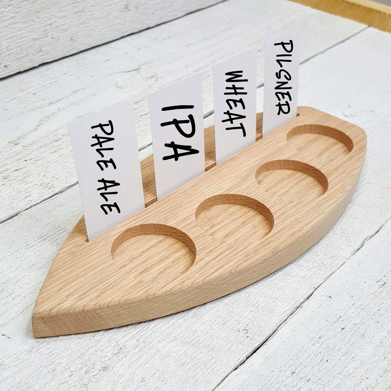 May include: Wooden beer flight with six individual cups and slots for cards. The cards are labeled "Pale Ale", "IPA", "Wheat", and "Pilsner".