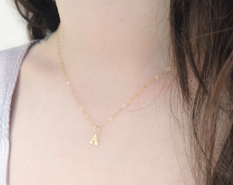 May include: A gold-coloured necklace featuring a small letter A pendant suspended from a 16-inch cable chain. The text on the image states: MODEL IS WEARING A 16" CABLE CHAIN. SHE IS 5' 2" 120 LBS.
