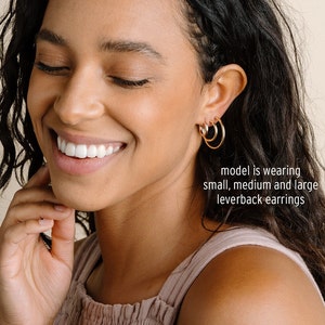 Peut inclure: Un mod&egrave;le porte trois boucles d'oreilles cr&eacute;oles &agrave; fermoir &agrave; levier dor&eacute;es de diff&eacute;rentes tailles. La l&eacute;gende indique "model is wearing small, medium and large leverback earrings".
