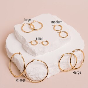 Peut inclure: Cinq paires de cr&eacute;oles dor&eacute;es de diff&eacute;rentes tailles, &eacute;tiquet&eacute;es "small", "medium", "large", "xlarge" et "xxlarge".