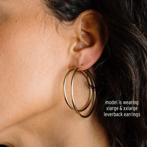 Peut inclure: Gros plan sur une oreille portant une paire de cr&eacute;oles dor&eacute;es &agrave; fermoir &agrave; levier. Le mod&egrave;le porte une paire de cr&eacute;oles de grande taille et une paire de cr&eacute;oles extra-larges. "model is wearing xlarge & xxlarge leverback earrings"