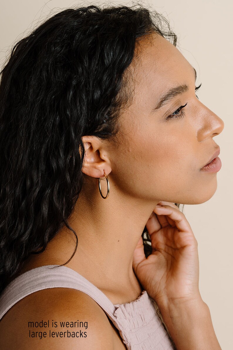 Peut inclure: Une mod&egrave;le porte de grandes boucles d'oreilles cr&eacute;oles en or. Les boucles d'oreilles sont simples et &eacute;l&eacute;gantes, et seraient un excellent ajout &agrave; toute collection de bijoux.