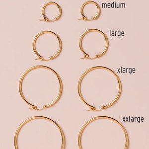 Peut inclure: Cinq paires de cr&eacute;oles dor&eacute;es de diff&eacute;rentes tailles, &eacute;tiquet&eacute;es "small", "medium", "large", "xlarge" et "xxlarge".