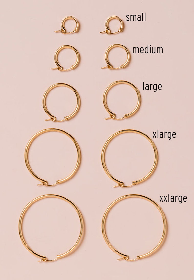 Peut inclure: Cinq paires de cr&eacute;oles dor&eacute;es de diff&eacute;rentes tailles, &eacute;tiquet&eacute;es "small", "medium", "large", "xlarge" et "xxlarge".