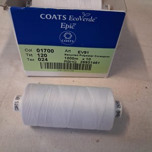 May include: A white spool of Coats EcoVerde Epic recycled polyester corespun thread positioned in front of a cardboard box containing multiple spools. The box label displays text including Col 01700, Tkt 120, Tex 024, Art EV91, and 1000m x 10.