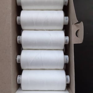 May include: A box of six white spools of Coats Epic thread. The spools are labeled with the brand name and the thread size.