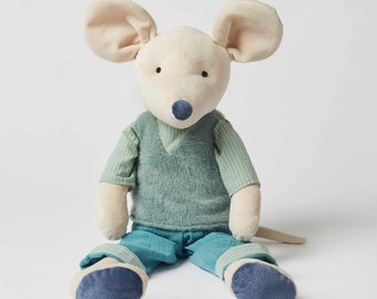 May include: A plush toy mouse wearing a green vest and blue pants. The mouse has a light brown body, large ears, and a blue nose.