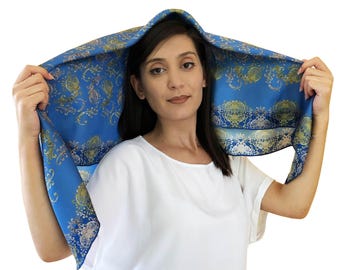 May include: A blue silk scarf with a gold and white floral pattern. The scarf is draped over a person's head and shoulders.