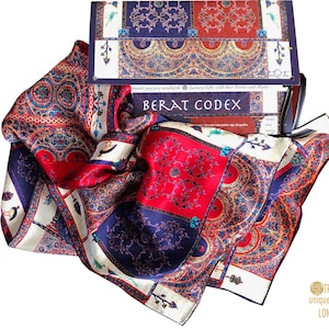 May include: A silk scarf with a colorful geometric pattern in shades of red, blue, and white. The scarf is folded and displayed on a white background with a box featuring the text "Berat Codex" and "Luxury Gifts with their Stories and Myths".