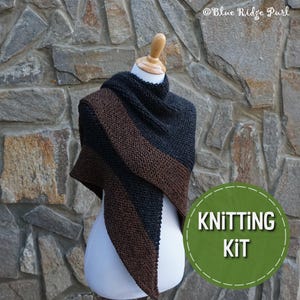 May include: A knitting kit for a brown and black triangular shawl. The shawl is displayed on a mannequin against a stone wall. The text "Knitting Kit" is in a green circle.