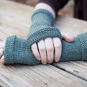 green hand knit wool fingerless gloves with smooth knit center section bordered with textured edges overall length of about 10 inches covers from first knuckle to middle forearm