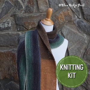 May include: A knitting kit featuring a brown, orange, and green striped scarf on a white mannequin. The scarf is made with a chunky yarn and has a simple stitch pattern. The text "Knitting Kit" is written in a green circle with a white outline.