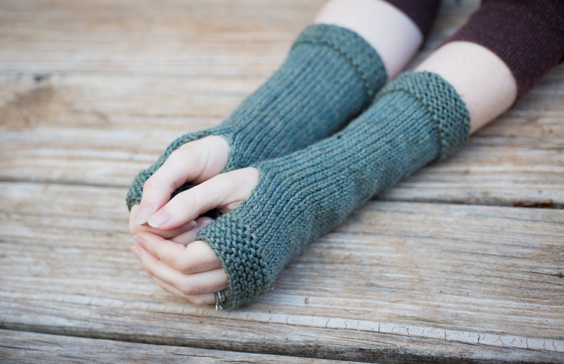 blue green knit wool arm warmers with thumbhole snug fitting and covers to the middle of  forearm