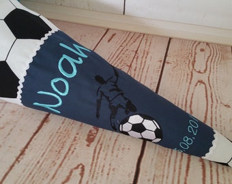 Peut inclure: Un cône scolaire bleu et blanc avec un motif de ballon de football. Le cône porte le nom "Noah" et la date "08.20" brodés.