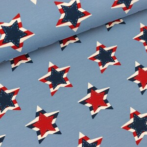 Könnte beinhalten: Blauer Stoff mit einem sich wiederholenden Muster aus roten und blauen Sternen. Die Sterne haben weiße Streifen und einen gestickten Umriss.