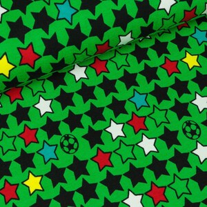 May include: Green fabric with a repeating pattern of black, white, red, yellow, and blue stars. A football is also included in the pattern.
