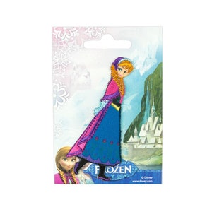 Könnte beinhalten: Bügeleisen-Aufnäher mit einem lila und blauen Kleid mit einem rosa Umhang. Die Figur Anna aus dem Film Frozen trägt das Kleid. Der Aufnäher hat eine glitzernde Oberfläche und ist von einem weißen Rand umgeben. Der Text "Frozen" ist unten auf dem Aufnäher aufgedruckt.