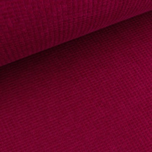 May include: Close-up of a deep crimson red fabric with a textured waffle weave pattern.