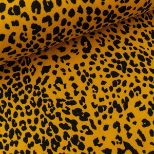 May include: A close-up of a yellow fabric with a black leopard print pattern.