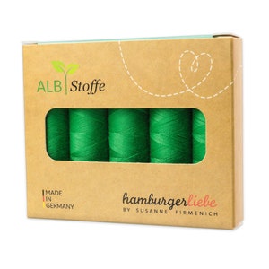 May include: A box of green sewing thread with the brand name "ALB Stoffe" and the text "hamburgerliebe by Susanne Firmenich" on the front. The box is made in Germany.
