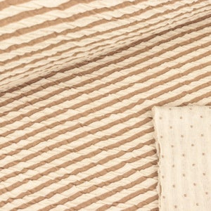 May include: Two pieces of fabric, one with brown stripes on a cream background and the other with small white dots on a cream background.