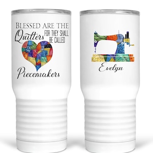 May include: White tumbler with a colorful patchwork heart and the text "Blessed are the Quilters for they shall be called Piecemakers". The other side of the tumbler has a colorful sewing machine with the name "Evelyn" underneath.
