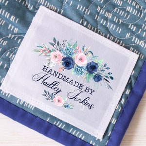 May include: A white fabric label with a floral design in shades of pink, blue, and green. The label reads "Handmade by Hadley Jenkins".
