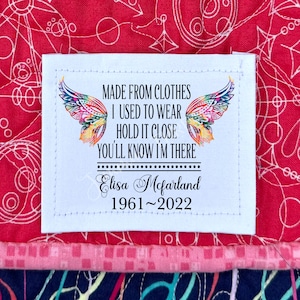May include: White fabric label with colorful butterfly wings and the text "MADE FROM CLOTHES I USED TO WEAR HOLD IT CLOSE YOU'LL KNOW I'M THERE Elisa Mcfarland 1961~2022".