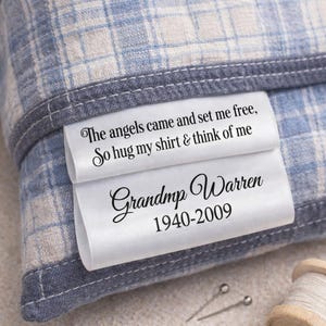 May include: A blue and white plaid fabric with a white label. The label reads "The angels came and set me free, So hug my shirt & think of me" and "Grandmp Warren 1940-2009".