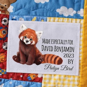 May include: A white rectangular label with a red panda illustration, stitched onto a colorful quilt. Text on the label reads "MADE ESPECIALLY FOR DAVID BENJAMIN 2023 BY Paityn Bird."