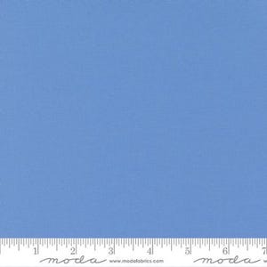 May include: A solid blue fabric swatch with a ruler marked in inches. The fabric is a light blue color.