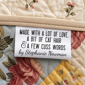 Etiqueta de satén divertida para quilters: «Hecha con mucho amor, un poco de pelo de gato y algunas palabrotas». Etiqueta personalizada para quilters con el nombre del fabricante.