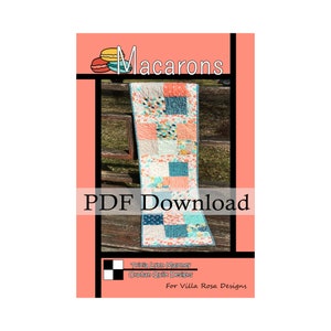 May include: A PDF download pattern for a quilt table runner called "Macarons" by Tricia Lynn Maloney for Villa Rosa Designs. The runner is made of colourful patchwork squares in shades of pink, blue, and white.
